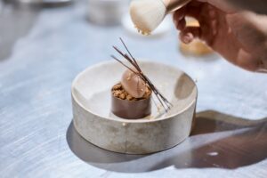 Ein Dessert, das verführt – feine Mandel-Pinienkern-Portwein-Kirschen kombiniert mit cremigem Schokoladenmousse und vollendet mit edlem Schokoladendekor. Eine harmonische Komposition aus Aromen und Texturen.  Dieses Dessert ist nur ein kleiner Einblick in die Köstlichkeiten, die wir im Workshop kreieren. 